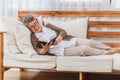 Happy & healthly retired smiling senior woman or pensioner reading book resting or sitting on couch or sofa at home. Eldery adult Royalty Free Stock Photo