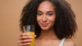 Happy healthy African American woman ethnic girl female model drinking fresh orange juice vitamin drink stretch hand Royalty Free Stock Photo