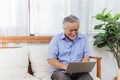 Happy healthy Asian senior elderly man working on computer at home. Retired grandfather enjoy learning or studying online course