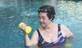 Happy and healthy Asian senior woman  working out in the swimming pool with yellow dumbbells. Elderly sports and active lifestyles Royalty Free Stock Photo