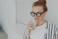 Happy healthy beautiful young redhead woman drinking water in morning at home