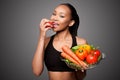 Happy healthy black asian woman eating vegetables