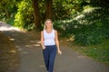 Happy healthy blond woman strolling along a shady lane