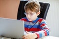 Happy healthy kid boy with glasses making school homework at home with notebook. Interested child writing essay with Royalty Free Stock Photo