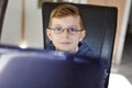 Happy healthy kid boy with glasses making school homework at home with notebook. Interested child writing essay with Royalty Free Stock Photo