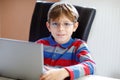 Happy healthy kid boy with glasses making school homework at home with notebook. Interested child writing essay with Royalty Free Stock Photo