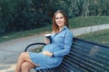 Pregnant young Caucasian woman wearing long blue dress and rustic country hat in park outside. Royalty Free Stock Photo