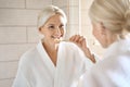 Happy smiling senior woman portrait with bamboo toothbrush looking at mirror.