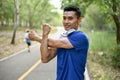 Happy Asian man in sportswear stretching his arms before running at a nature park Royalty Free Stock Photo