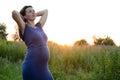 Happy healthy pregnancy and maternity. Portrait of pregnant young caucasian woman wearing long blue dress posing in park Royalty Free Stock Photo