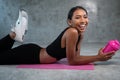 Happy healthy smiling woman holding protein shake relaxing on the pink yoga mat at the gym