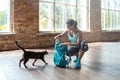 Happy sporty young woman unpack backpack in modern gym playing with funny cat Royalty Free Stock Photo