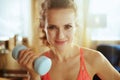 Happy healthy woman with dumbbell in modern living room