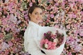 Happy healthy woman smiling and holding colorful pink color flower bouquet on floral spring or summer background, studio fashion Royalty Free Stock Photo