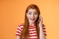 Happy hear friend voice, calling abroad. Amused surprised cute redhead cheerful girl pick up phone, hold smartphone ear