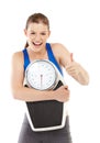 Happy with her weight. Portrait of a pretty teenage girl carrying a scale and making a thumbs-up sign. Royalty Free Stock Photo