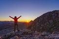 Happy hiker girl meets sunrise with raised arms high in the mountains Royalty Free Stock Photo