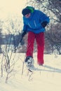 Happy hiker in snowshoes walks through the winter forest