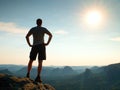 Happy hiker is standing on sharp cliff in rock empires park and watching over the misty and foggy morning valley to Sun.