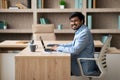 Happy hindu businessman at desk managing emails on laptop indoor