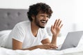 Happy hindu man chilling in bed, having online party