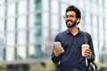 Happy hindu millennial man employee going to office, drinking coffee