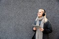 Happy hippie girl browsing a tablet and listening to the music with headphones leaning on a wall in the street. Hipster woman Royalty Free Stock Photo