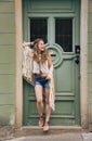 Happy hippy-looking woman standing outdoors against wooden door