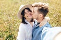 Happy hipster couple making selfie and kissing in sunny mountains. Stylish young family taking photo in travel and enjoying hiking Royalty Free Stock Photo