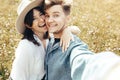 Happy hipster couple making selfie and smiling in sunny mountains. Stylish young family taking photo in travel and enjoying hiking Royalty Free Stock Photo