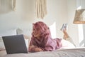 Happy hipster gen z teen girl with pink hair watching movie on laptop in bed.