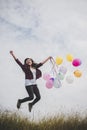 Happy hipster girl jumping with colorful toy balloons outdoors. Royalty Free Stock Photo