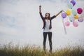 Happy hipster girl jumping with colorful toy balloons outdoors. Royalty Free Stock Photo