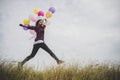 Happy hipster girl jumping with colorful toy balloons outdoors. Royalty Free Stock Photo