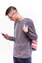 Happy hipster guy with backpack and using a smart phone to listen music with headphones Royalty Free Stock Photo