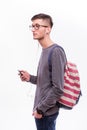 Happy hipster guy in glasses with backpack using a smart phone to listen music Royalty Free Stock Photo