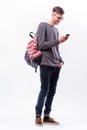 Happy hipster guy in glasses with backpack using a smart phone to listen music with headphones Royalty Free Stock Photo