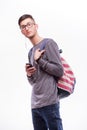 Happy hipster guy in glasses with backpack using a smart phone to listen music Royalty Free Stock Photo