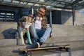Happy hipster man skateboarder resting and sitting with loving dog Royalty Free Stock Photo