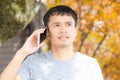 Happy hipster man walking in autumn park using mobile phone Royalty Free Stock Photo