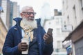 Happy hipster senior businessman using mobile phone while drinking coffee on winter day - Focus on face Royalty Free Stock Photo