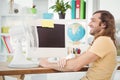 Happy hipster sitting by electric fan on computer desk Royalty Free Stock Photo