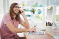 Happy hipster using mobile phone at computer desk Royalty Free Stock Photo