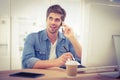 Happy hipster using mobile phone while sitting at desk Royalty Free Stock Photo