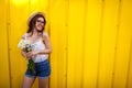 Happy hipster girl wearing glasses and hat with flowers against yellow background. Summer outfit. Copy Space. Royalty Free Stock Photo