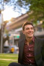 Happy Hispanic businessman thinking and sitting with nature in city Royalty Free Stock Photo