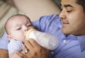 Happy Hispanic Father Bottle Feading His Son Royalty Free Stock Photo