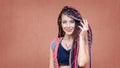 Happy hispanic girl with braids and tattoo smiling at camera outdoors with colorful background Royalty Free Stock Photo