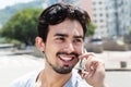 Happy hispanic guy in a grey shirt at phone in city Royalty Free Stock Photo