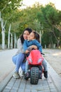 Happy Hispanic mother hugging her son on a balance bike in a park. Royalty Free Stock Photo